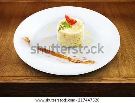 Health vegetarian rice with tomato and butter on a round plate on wooden table