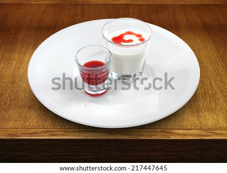 Smooth and creamy panna cotta with strawberry and raspberry sauce in a small glass on wooden table