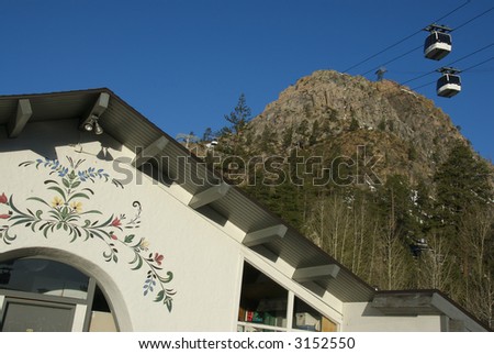 A Scenic ski lodge sits against a tall mountain peak and gondola