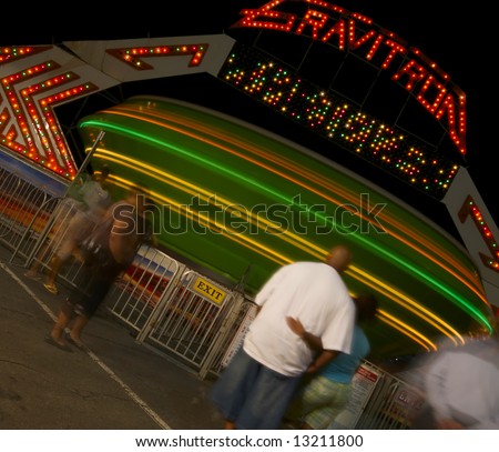 An African American couple stand in line and wait for their turn on a spinning carnival ride at night
