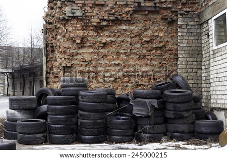 Old used tires stocked for recycling at red brick wall