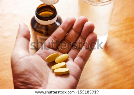 Pills spilling from a bottle into a hand.