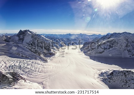 Swiss Aletch glacier crossing flows helicopter view in winter under bright sunshine