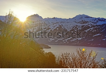 Sun rising behind Eiger peak in Jungfrau region of Switzerland in winter with sun flares in lens
