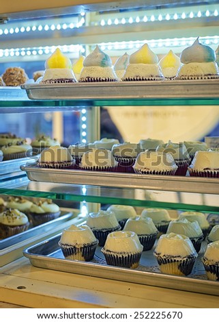 Various cupcakes on the bakery storefront with blurred background