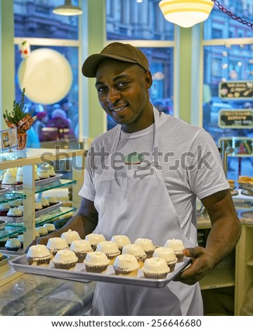 Black man with cupcakes on tray in the bakery counter