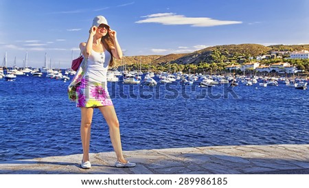 Young nice girl in panama cap and sunglasses and hairs on the wind on the sunny mediterranean sea quay