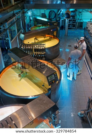 GRUYERE, SWITZERLAND - DECEMBER 31, 2014: Gruyere cheese processing. It is a hard yellow cheese, named after the town of Gruyeres in the canton of Fribourg, Switzerland