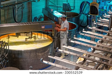 GRUYERES, SWITZERLAND - JANUARY 2, 2015: Heating milk in a copper kettle to make a famous Gruyere cheese. It is a hard yellow cheese, named after the town of Gruyeres in Switzerland