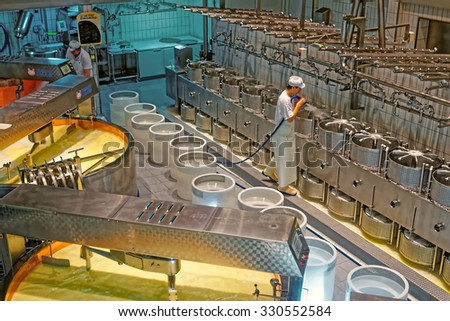 GRUYERES, SWITZERLAND - JANUARY 2, 2015: Worker of the cheese-making factory of Gruyeres cleaning cheese molds. Gruyere is a famous swiss cheese generally known as one of the best cheeses for baking