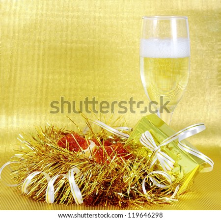 A glass of champagne and sandwiches with red caviar on a gold background side view.