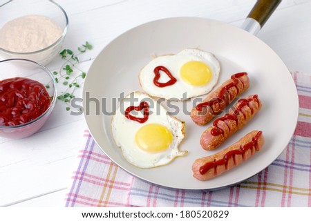 Sausage and fried egg with ketchup in a ceramic pan.
