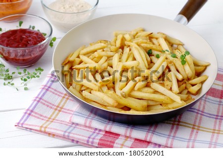 Fried potatoes in a ceramic pan angle view.