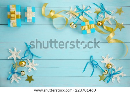 Festive background. Gift boxes with golden ribbons and crocheted snowflakes on a blue wooden background top view.
