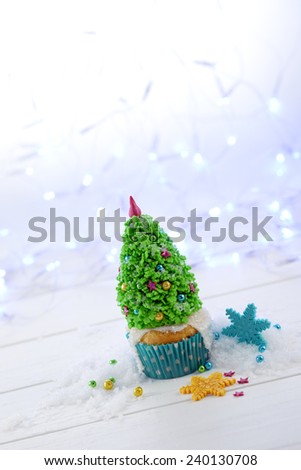 Cupcake decorated with Christmas tree on the Christmas lights background vertical format diagonal crop.