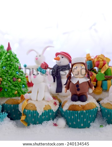 Festive cupcakes decorated with sugar figures of a kid in a fur hat and a rabbit selective cropping.