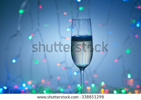 Bubbles of champagne in a flute glass on the festive dark background.