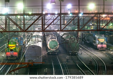 Cars and trains staying on rails at night time in depot