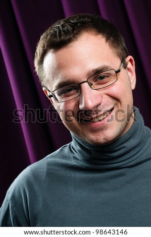 Smiling man with glasses portrait with purple curtain on background