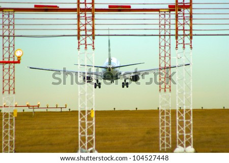 Photo of an airplane just before landing. Runway lights can be seen in the foreground.