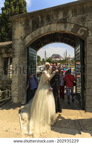 ISTANBUL, TURKEY - MAY 25:  A very  happy couple leave the Blue Mosque after  their wedding.  In the background    Hagia Sophia   on May 25, 2014 Istanbul, Turkey.
