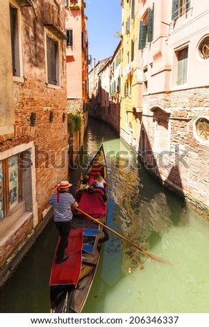 ITALY, VENICE - JUN 1 2014: Gondolier on a gondola on the Grand Canal taking tourist for a ride. Venice. Gondola\'s are a major mode of touristic transport in Venice, Italy .