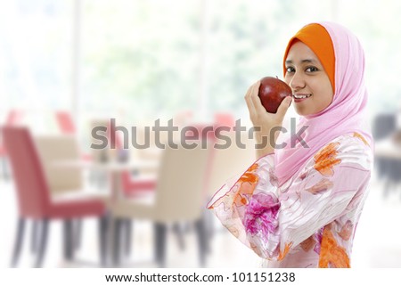 Young Muslim woman eating apple, healthy eating concept
