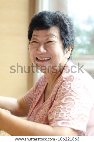 Happy 60s Senior Asian Woman dining indoors