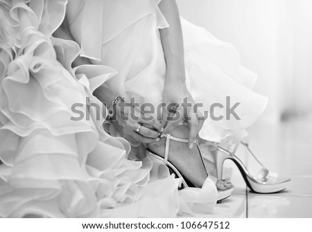 The bride is putting on her shoes for the wedding day.