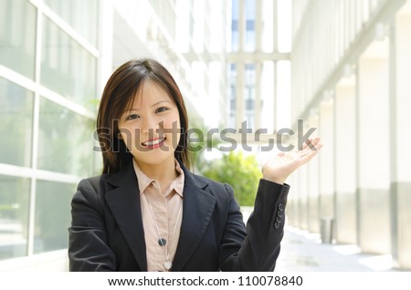 Mixed race Asian woman showing welcome sign over modern building