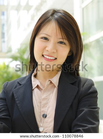 Young Asian executive standing outside office building