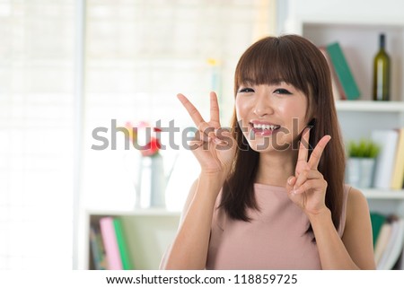 Cute Asian with peace sign standing inside house