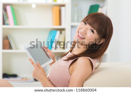 Happy Asian girl using tablet computer indoor
