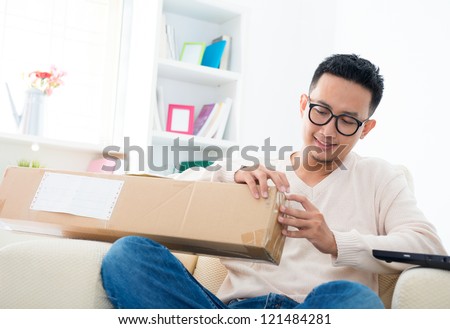 Southeast Asian male received an express parcel and open it at home
