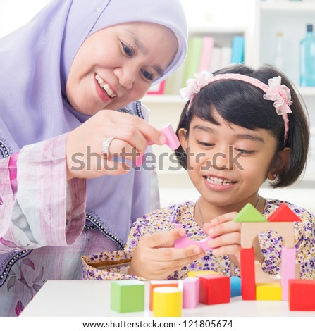 Muslim family building wooden house toy. Southeast Asian family living lifestyle.