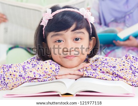 Muslim girl reading book at home. Southeast Asian family living lifestyle