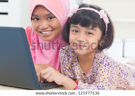 Southeast Asian children surfing internet at home. Malay Muslim girls