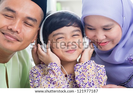 Southeast Asian family listen mp3, sharing headphone. Muslim family living lifestyle