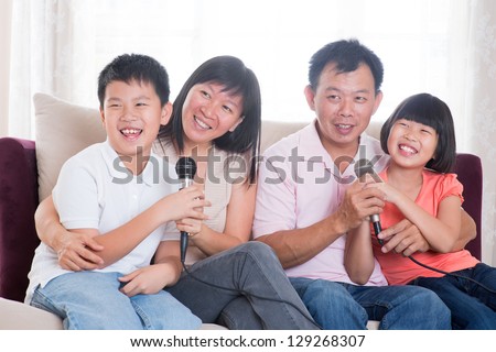 Family at home. Portrait of a happy Asian family singing karaoke through microphone in the living room
