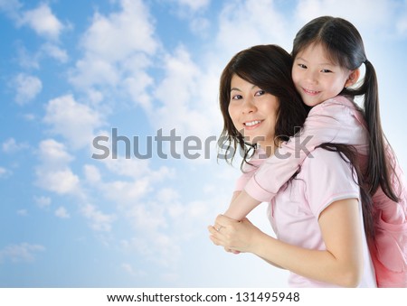 Asian family outdoor fun. Asian mother piggyback her daughter at a nice summer outdoor