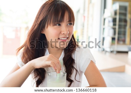 Young Asian woman enjoying drinks with friend at cafe.