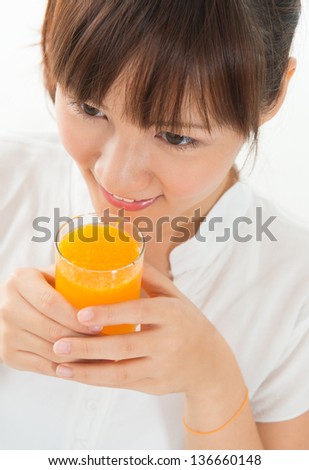 Young Asian female drinking orange juice, isolated on white.