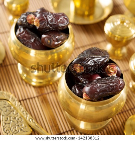 Dried date palm fruits or kurma, ramadan food which eaten in fasting month. Pile of fresh dried date fruits in golden metal bowl.