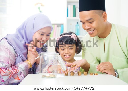 Islamic banking concept. Southeast Asian family counting money at home. Little Malay girl and parents saving money. Muslim father, mother and daughter living lifestyle.