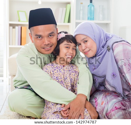 Muslim parents hugging child. Southeast Asian Malay family lifestyle. Happy smiling father mother and daughter.
