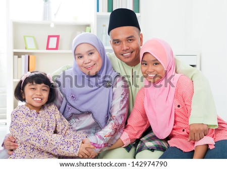 Happy Asian family at home. Muslim family having fun indoors. Southeast Asian parents and children smiling.