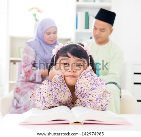 Malay girl reading book. Southeast Asian family at home. Muslim parents and child living lifestyle.