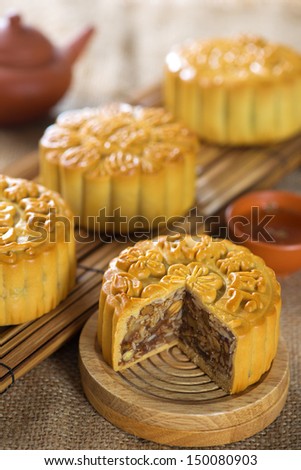 Chinese mid autumn festival foods. Traditional mooncakes on table setting with tea set.  The Chinese words on the mooncakes means assorted fruits nuts, not a logo or trademark.