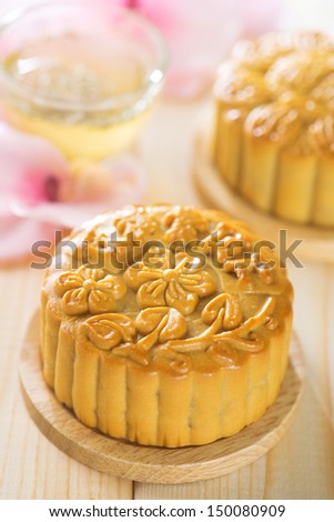 Chinese mid autumn festival foods. Traditional mooncakes on table setting with flower tea.  The Chinese words on the mooncakes means assorted fruits nuts, not a logo or trademark.