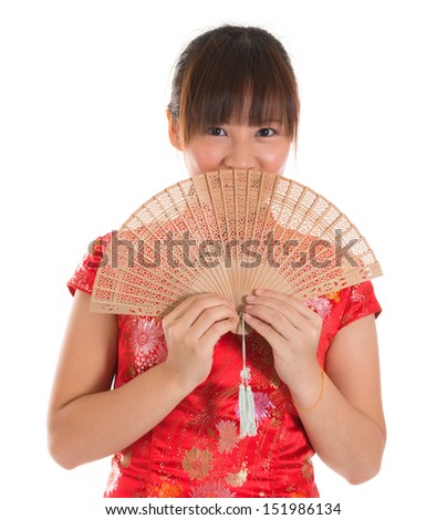 Asian woman with Chinese traditional dress cheongsam or qipao holding Chinese fan covering part of face. Chinese new year concept, female model isolated on white background.